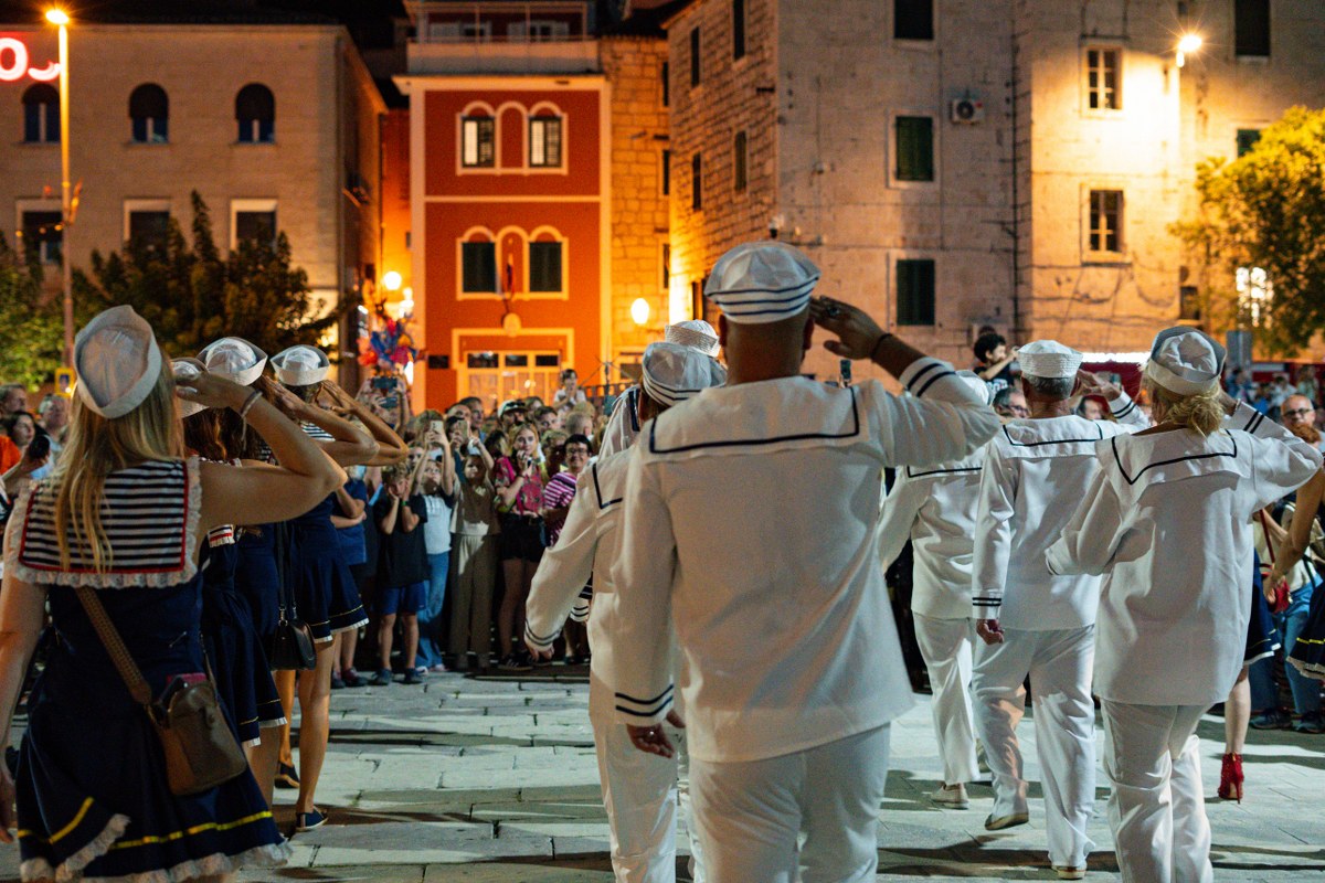Group of people in white naval uniforms at a night event