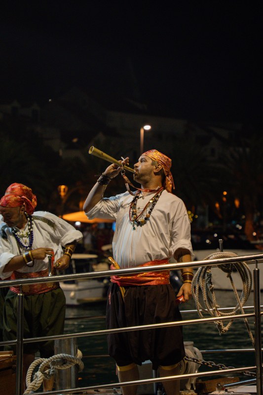 Man in costume playing a trumpet on a boat at night