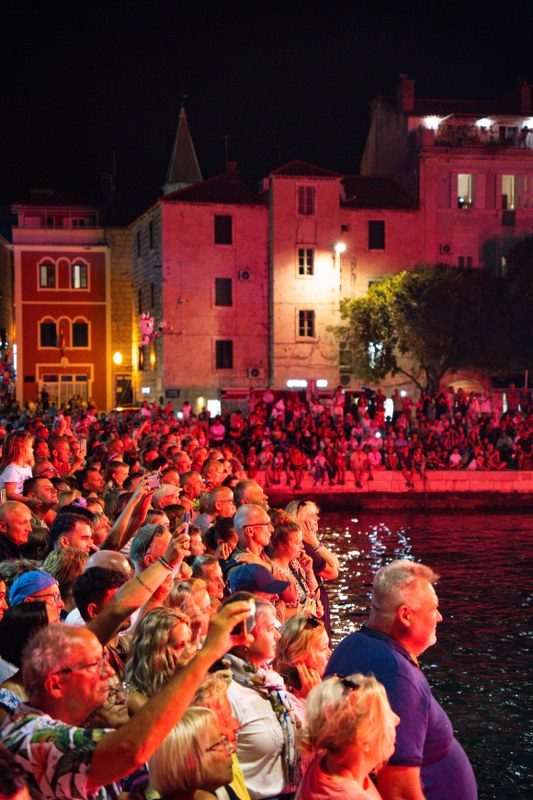 Crowd watching a night event with illuminated red buildings