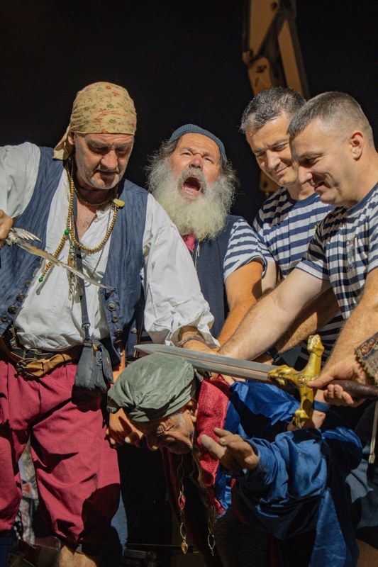 Two men in costume, one with a long white beard, at a night event depicting naval battle