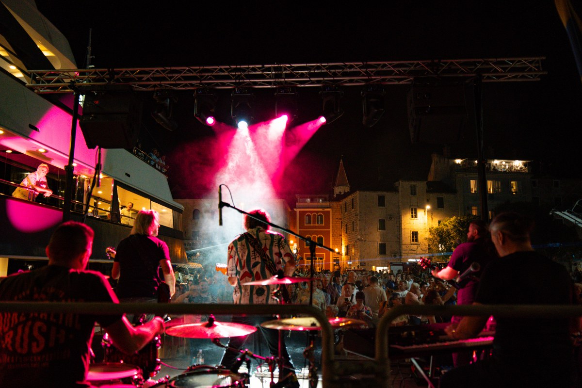 Musicians performing on a stage lit with pink lights at night
